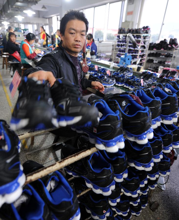 A staff member works at a factory producing shoes for export in Daxi Town of Wenling City, east China's Zhejiang Province, Dec.1, 2011. 