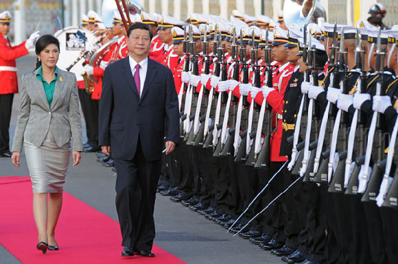 Vice-President Xi Jinping, accompanied by Thai Prime Minister Yingluck Shinawatra, reviews an honor guard in Bangkok on Thursday. Xi is on a three-day visit to the Southeast Asian nation. [China Daily] 