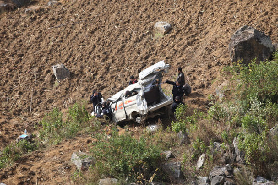 Police at the crash scene of a minivan carrying 12 students that plunged into a nearly 78-meter-deep valley in the county of Guangnan, the Wenshan Zhuang and Miao autonomous prefecture, Yunnan province, on Saturday. [Photo/China Daily]