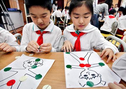 Students mark red for private parts and green for areas that can be touched at a sex education lesson at a primary school in Shanghai on October 24, 2011. [File photo] 2011年10月24日，上海某小学的性别教育课堂上，学生们在身体轮廓图上贴标签，可以触摸的部位贴绿的，不可以触摸的贴红的。