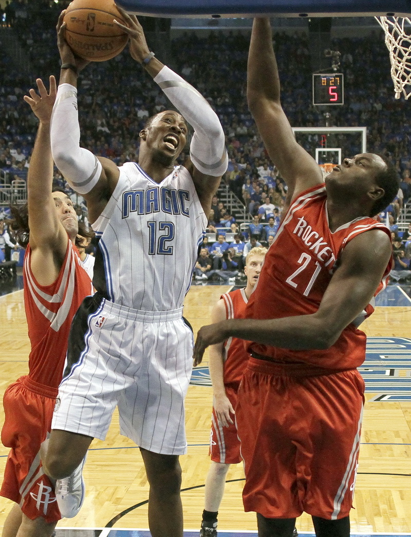 Orlando Magic center Dwight Howard gets off a shot between Houston Rockets' Luis Scola, (left), and Samuel Dalembert during the first half of an NBA basketball game Monday, Dec. 26, 2011, in Orlando, Florida.