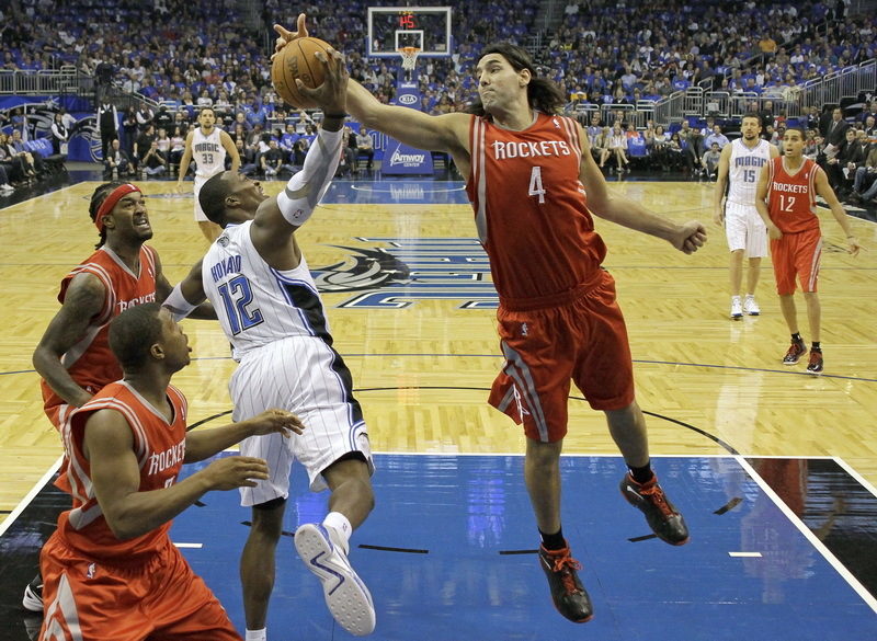 Houston Rockets' Luis Scola battles for a rebound with Orlando Magic center Dwight Howard during the first half of an NBA basketball game Monday, Dec. 26, 2011, in Orlando, Florida.