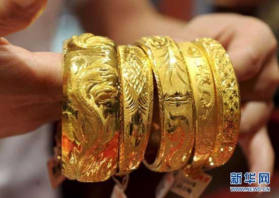 An employee at a gold store in Yiwu, located in east China's Zhejiang province, shows gold jewelry.