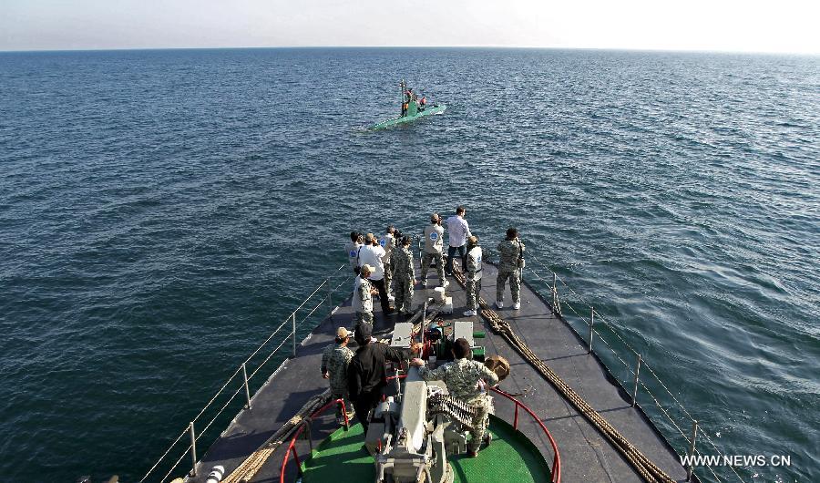 Soldiers and local journalists look at a submarine during Iranian naval maneuvers dubbed Velayat 90 on the Sea of Oman, Iran, Dec. 27, 2011. [Ali Mohammadi/Xinhua]