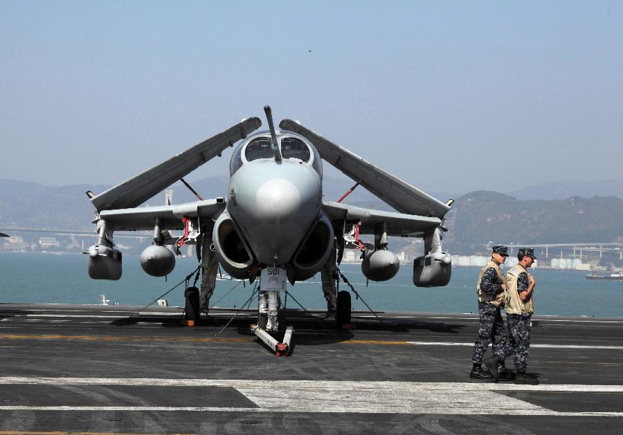 Two US Navy servicemen pass by a warplane on the flight deck of the American aircraft carrier USS Carl Vinson in Hong Kong, south China, Dec. 27, 2011. The nuclear-powered supercarrier berthed in the water area of Hong Kong on Tuesday, starting a three-day visit for replenishment. [Jin Yi/Xinhua] 