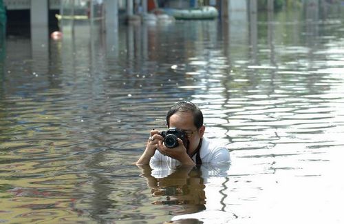 A man takes pictures in the floodwaters in Bang Khun Thian district in Bangkok, Thailand, Nov. 18, 2011. [Rachen Sageamsak/Xinhua] 