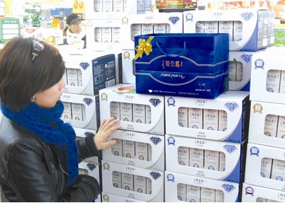 A customer chooses a Mengniu milk gif box in super market. [File photo]