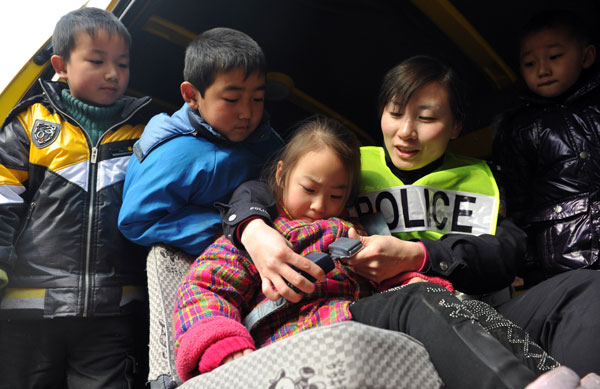 Xu Zhongmei, an officer at the Shuijiahu police station in Changfeng county, Anhui province, teaches students from a local kindergarten how to use the seat belt in a school bus on Monday. [Photo / Xinhua]