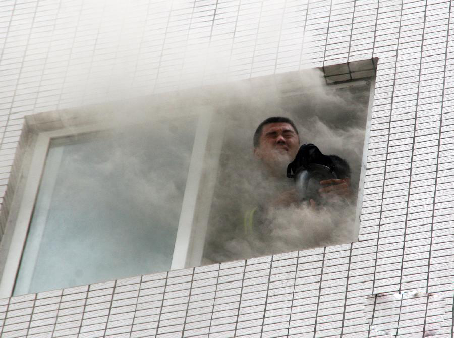 Xia Lin, deputy chief of the firefighting department of Qinzhou, Guangxi Zhuang Autonomous Region, shields a baby from heavy smoke using his breathing apparatus after fire broke out in a building on May 22, 2011.