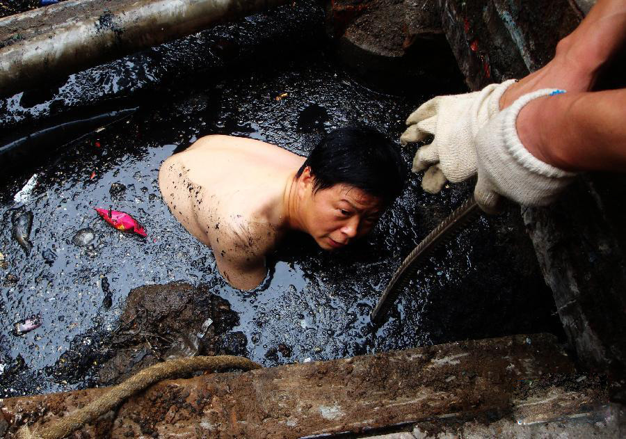 Liu Yueqing, a worker from Wuhan Power Supply Company, jumps into the ditch water to fix the electric cable only wearing his underwear on July 13, 2011.