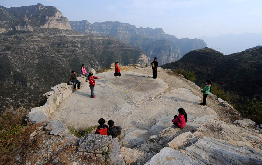 President of a primary school in Pingshun County, Shanxi Province, leads his students to play at the 'playground' – a huge slab of stone on August 9, 2011.
