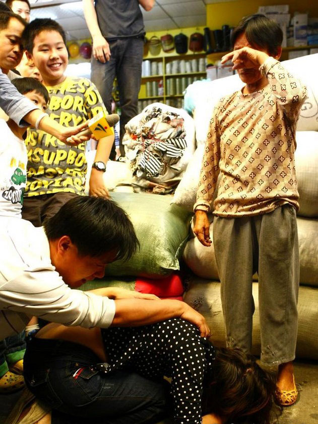 The parents of Wang Yue, a toddler who was run over by two vehicles in Guangdong Province on Oct. 13, 2011, kneels in front of Chen Xianmei to thank the street sweeper for moving their daughter to a safe place after she was ignored by 18 other pedestrians. 