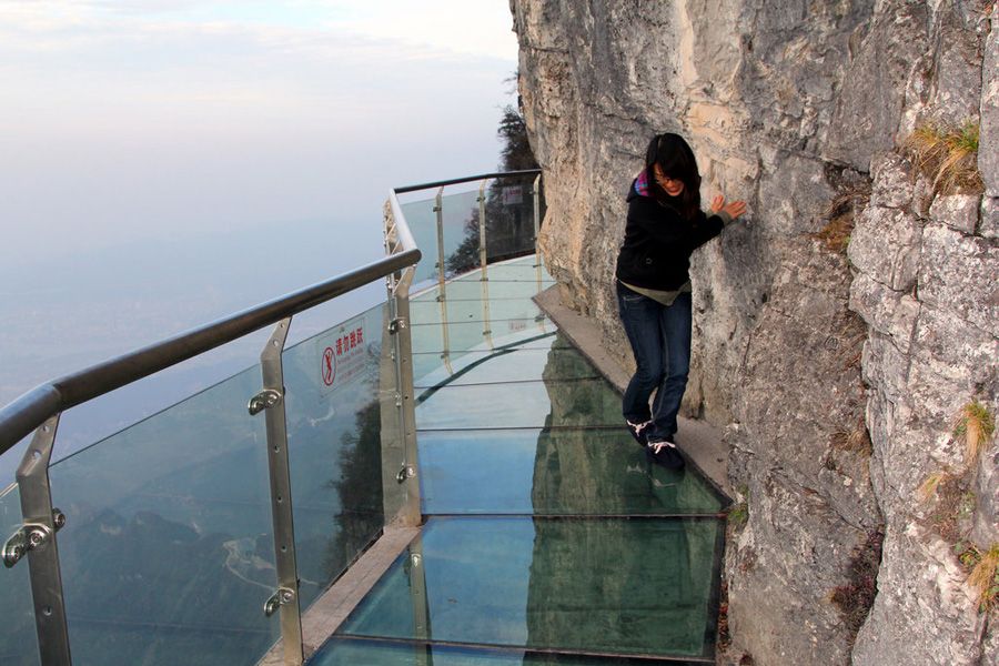 A tourist gingerly makes her way on a glass skywalk built along the cliffs of Tianmen Mountain in Zhangjiajie, Hunan Province, on Nov. 9, 2011.
