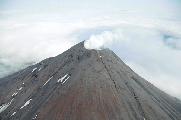 An aerial photograph shows the Cleveland Volcano during the time a small lava flow, or dome, was accumulating in the summit crater as the 660 foot (182.88m) wide summit crater emits a white, largely steam condensate cloud in this Aug 8, 2011 file photo. The remote volcano in Alaska's Aleutian islands erupted early on Dec 29, 2011 spouting an ash cloud 15,000 feet(4572m) into the sky and prompting an air-traffic alert, scientists said. [Photo/Agencies]