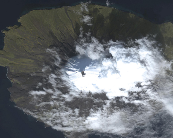 A true-color satellite image of Cleveland Volcano collected by the Worldview-2 sensor on Oct 7, 2011. The summit of the volcano is mostly snow-covered, and the growing lava dome is seen as the dark feature in the center of the image. Some snow-free ground is observed on the southern upper flanks of the volcano, just south (below) of the crater. A faint steam and gas plume is observed moving towards the northeast (upper-right). [Photo/Agencies]