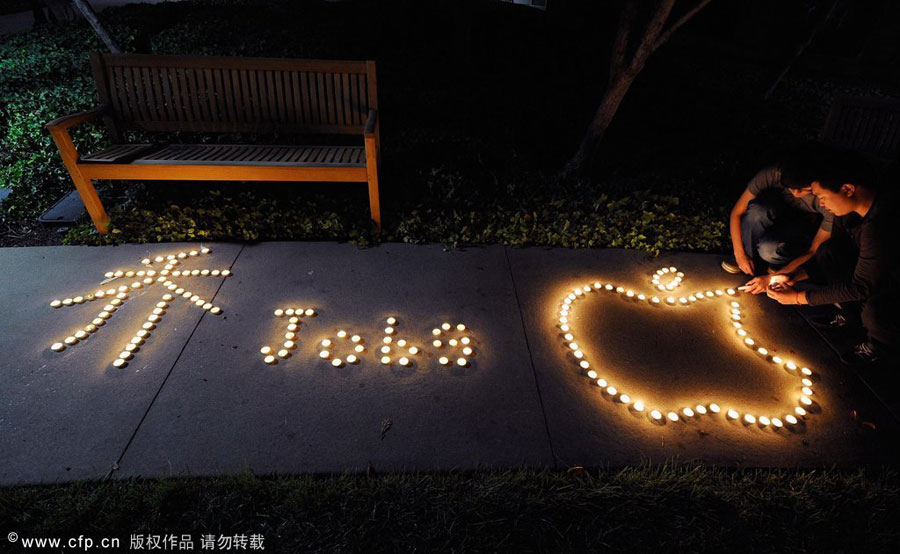 Chinese exchange students from nearby De Anza College use candles to create the Apple logo and Steve Jobs' last name in Chinese characters at a makeshift memorial for Steve Jobs at the Apple headquarters on Oct. 5, 2011 in Cupertino, California. [CFP] 