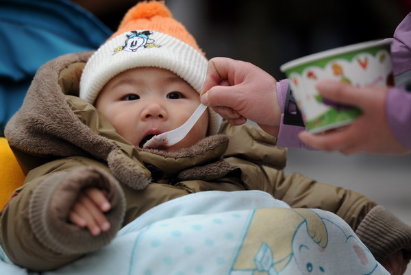 A child is spoon-fed Laba rice porridge at a temple in Nanjing, East China's Jiangsu province, Jan 1, 2012. The Laba Festival, which falls on the eighth day of the twelfth month on the lunar calendar, commemorates Sakyamuni Buddha's enlightenment. Chinese celebrate the day by eating Laba porridge, which is made with rice, nuts, cereal and dried fruit.