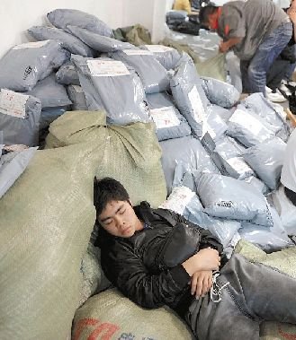 A courier takes a rest on a parcel mountain. [File photo]