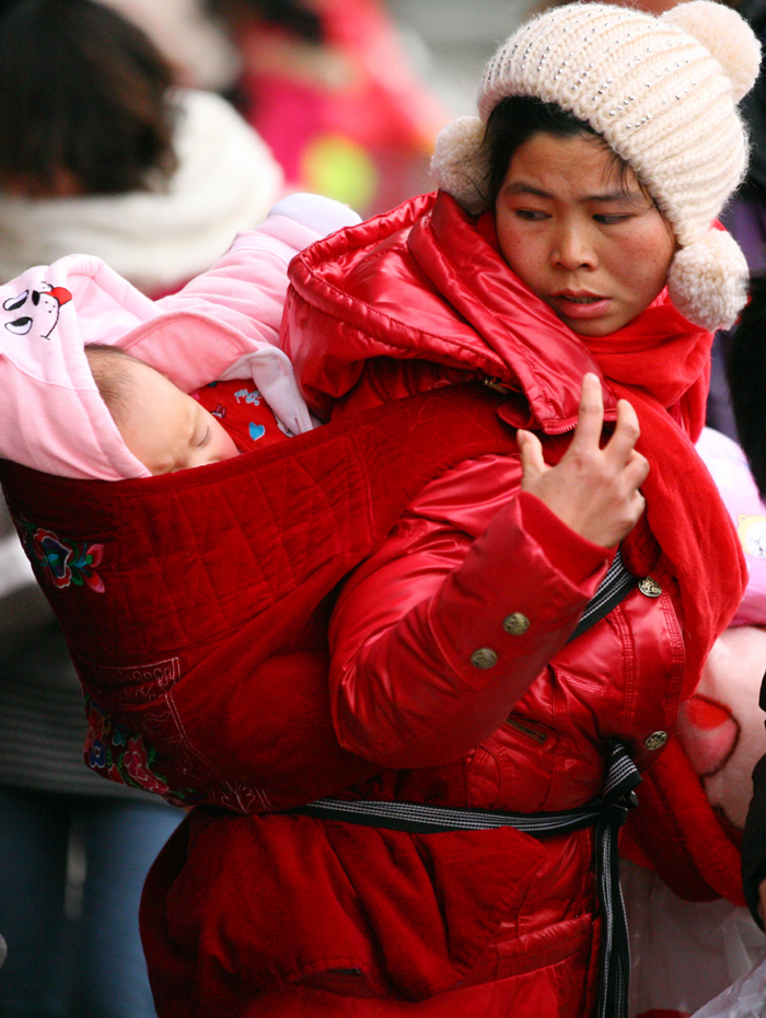 Spring Festival, or Chinese Lunar New Year, which this year falls on Jan. 23, is traditionally the time when millions of Chinese rush home for family reunions and celebrations. This picture shows a baby fast asleep as its mother battles with the crowds in Nanjing, Jiangsu Province, on Jan. 3. [Xinhua photo]