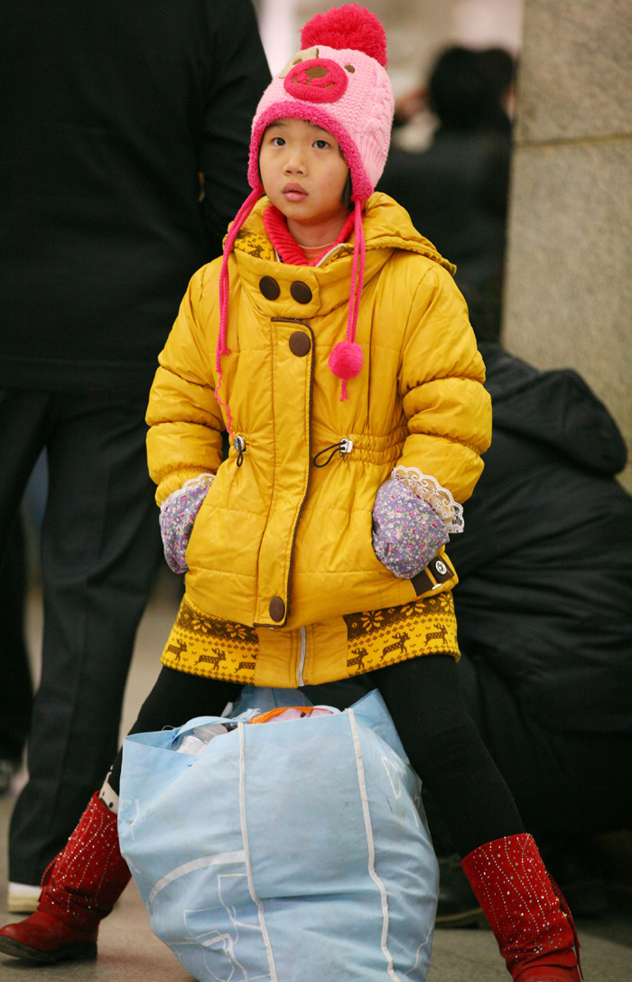 Spring Festival, or Chinese Lunar New Year, which this year falls on Jan. 23, is traditionally the time when millions of Chinese rush home for family reunions and celebrations. Here, a child waits for the off with a mixture of impatience and tired resignation in Nanjing, Jiangsu Province, on Jan. 3. [Xinhua photo]