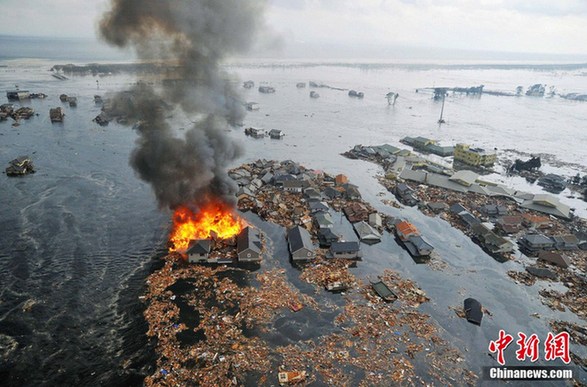 Numerous houses are left flooded and ablaze in Natori, Miyagi after a massive earthquake and tsunami jolted Japan on March 11, 2011. [Chinanews.com]