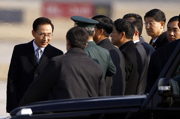 South Korean President Lee Myung-bak (L) shakes hands with officials after arriving at Beijing airport January 9, 2012. [Agencies] 