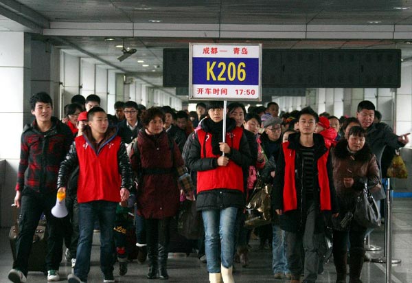 A volunteer guides passengers to their train at Chengdu Railway Station in Chengdu, Sichuan Province, Jan. 7, 2012. Starting from Jan. 8, 2012, China's transport system will undergo a 40-day travel rush, which is characterized by a hightened passenger flow around the time of the oncoming Chinese New Year.