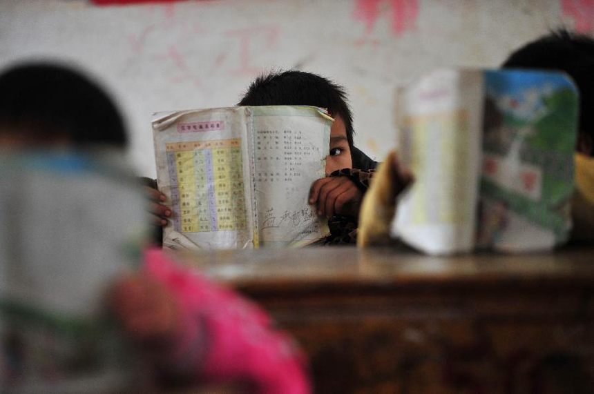 Lan Chengshi, a seven-year-old boy, studies in class at the school of Minxin Village in Mashan County, southwest China's Guangxi Zhuang Autonomous Region, Jan. 6, 2012. Every day, Lan has to leave home very early in the morning and climbs over hills for hours to go to school. 