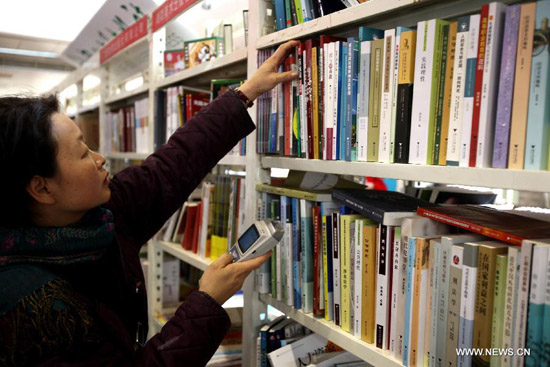 A dealer selects books during the 2012 Beijing Book Expo at the China International Exhibition Center in Beijing, capital of China, Jan. 9, 2012. A total of 762 publishing enterprises and book wholesalers participated in the four-day book expo. [Xinhua/Jin Liwang]