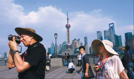 Tourists visit the Bund in Shanghai. Those who arrive by air have helped support Asia's international passenger market and China's domestic demand, which Credit Suisse expects to remain resilient this year. [China Daily]