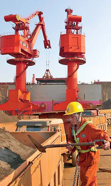 Workers unload imported iron ore at Qingdao port, Shandong province. China launched a physical iron ore spot trading platform on Monday. [China Daily]