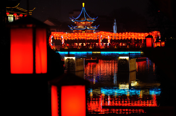 Nanjing residents enjoy the festive lantern decorations at the Gate of China area along the banks of the Qinhuai River in Nanjing, capital city of East China's Jiangsu province, on Jan 19, 2012. More than a hundred large sets of lantern scenes and over 400,000 individual lanterns will dress up the banks of the Qinhuai River during the fair, Jan 19 to Feb 9.