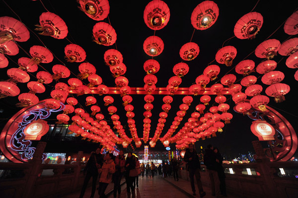 Nanjing residents enjoy the festive lantern decorations at the Gate of China area along the banks of the Qinhuai River in Nanjing, capital city of East China's Jiangsu province, on Jan 19, 2012. More than a hundred large sets of lantern scenes and over 400,000 individual lanterns will dress up the banks of the Qinhuai River during the fair, Jan 19 to Feb 9.