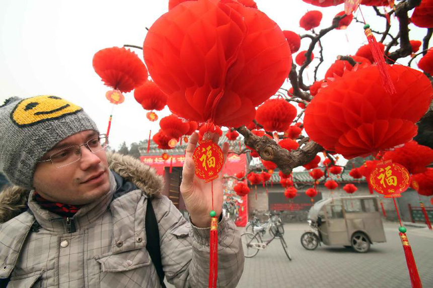 A foreign visitor views Chinese traditional decoration for Spring Festival at the Ditan Park in Beijing, capital of China, Jan. 18, 2012. With the coming of Spring Festival, the festal atmosphere has been spread all over China. (