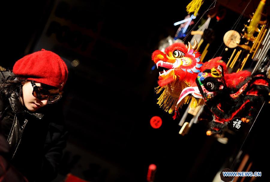 A woman chooses festival ornament in a shop at China Town in New York, the United States, Jan. 20, 2012. Shopkeepers sold various ornaments in their shops at China Town for the approaching Spring Festival.