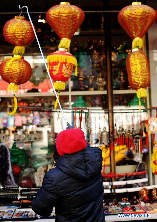 A shopkeeper hangs a lantern in front of the shop at China Town in New York, the United States, Jan. 20, 2012. Shopkeepers sold various ornaments in their shops at China Town for the approaching Spring Festival.