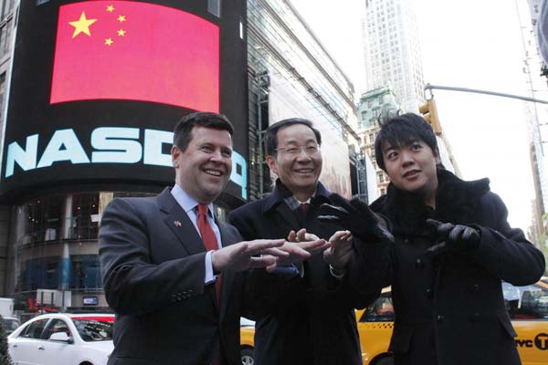 Chinese Consul General in New York Sun Guoxiang (C), pianist Lang Lang (R), and Nasdaq Senior Vice-President Robert McCooey (L) pretend to play piano in front of the Nasdaq MarketSite screen on the Times Square for photos on Jan 20, 2012 in New York. [Photo/Xinhua]