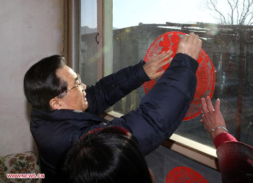 Chinese President Hu Jintao helps put a red papercutting on a window at the residence of Shao Qicheng, an 85-year-old army veteran, in Tianxianyu Village of the Huairou District in Beijing, capital of China, Jan. 22, 2012. Hu visited grassroots urban and rural areas in Beijing on Sunday, the eve of the Spring Festival, extending greetings to the people and celebrating with them the Chinese Lunar New Year. 