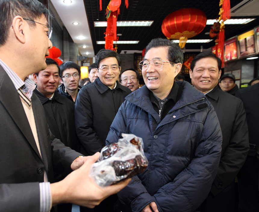 Chinese President Hu Jintao (R Front) visits a time-honored store famous for braised pork on Qianmen shopping street in Beijing, capital of China, Jan. 22, 2012. Hu visited grassroots urban and rural areas in Beijing on Sunday, the eve of the Spring Festival, extending greetings to the people and celebrating with them the Chinese traditional lunar New Year. 