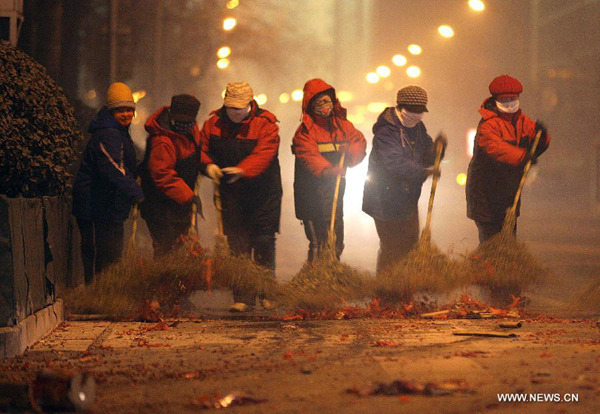Sanitation workers clean the firecracker residue on a street in Beijing on Jan. 23, 2012. A good deal of firecrackers has been set off on the eve before Spring Festival as a kind of Chinese folk tradition. 