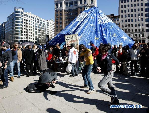 Occupy D.C. protesters dance in front of the McPherson statue covered with a blue water-proof cloth at McPherson Square in Washington D.C., Jan. 30, 2012. Defiant Occupy D.C. protesters on Monday vowed to continue with their encampment in the U.S. capital as the deadline for decampment passed. [Fang Zhe/Xinhua]