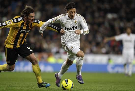 Real Madrid's Mesut Ozil from Germany, left, vies for the ball with Zaragoza's Maurizio Lanzaro from Italy during their Spanish La Liga soccer match at the Santiago Bernabeu stadium in Madrid, Saturday, Jan. 28, 2012. 