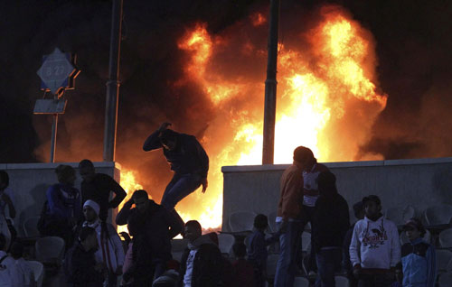 A soccer fan flees from a fire at Cairo stadium Feb, 1, 2012. Crowds set parts of the stadium on fire in reaction to a soccer pitch invasion during another soccer match held at the Egyptian city of Port Said. [Agencies] 