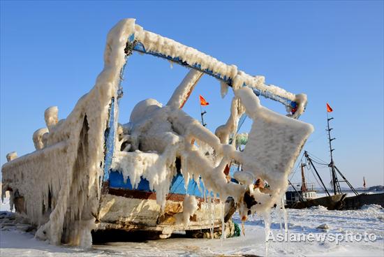 Surging sea water frozen on a fishing boat stuck at Beihai port in Dalian, Northeast China's Liaoning province, on Feb 1, 2012. [Asianewsphoto]
