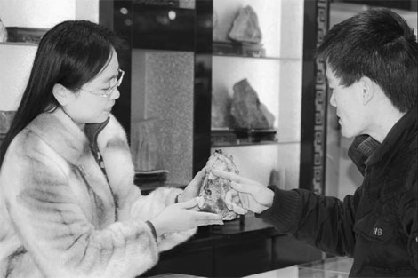 Zhou Weixia, a gem shop owner, shows a man a rough sapphire stone in Changle, Shandong province. The county now abounds with 450 square kilometers of sapphire-rich land with deposits totaling more than one billion carats.[China Daily]