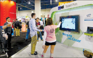 Visitors at a consumer technology exhibition in Las Vegas play a video-tennis game on a SmartTV produced by the Chinese IT giant ZTE Corp. Many companies aim to enter the sector on expectation that it will expand rapidly in the coming years. 