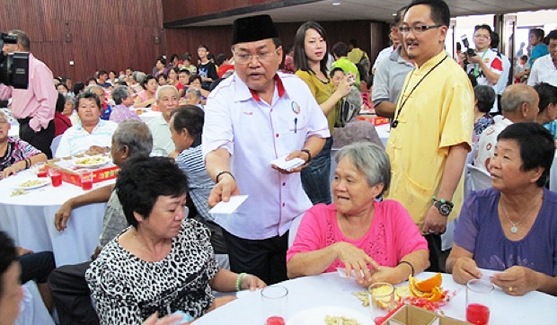 A Perkasa member hands white packets to Chinese at a Spring Festival gathering in Malaysia. 