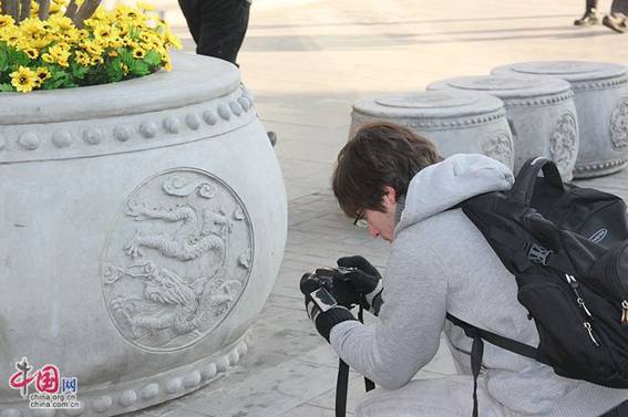 A foreign tourist is taking a photo of the engraving of Chinese dragon in Qianmen, a famous business street in Beijing, during the Spring Festival of 2012. 2012年春节期间，一名外国游客在北京前门商业街拍摄中国的龙纹饰。