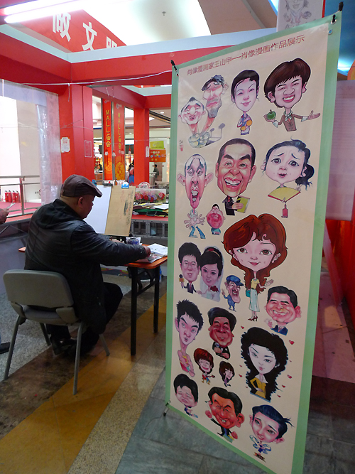 A portrait caricaturist is drawing a picture in an indoor temple fair in the Golden Resources Shopping Mall located in the northwest part of Beijing during the Spring Festival 2012, where visitors can enjoy the charm of the traditional Chinese arts and the delicacy of local snacks. [By Xu Lin / China.org.cn]