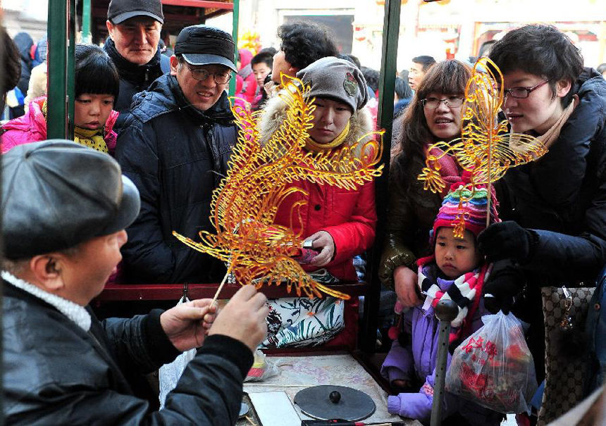 People watch the making of dragon-shaped sugar paintings at a temple fair held during the Spring Festival holiday in Tianjin, north China, Jan. 25, 2012. The Spring Festival, or the Chinese Lunar New Year, which fell on Jan. 23 this year, marked the start of the Year of Dragon, according to the Chinese zodiac.